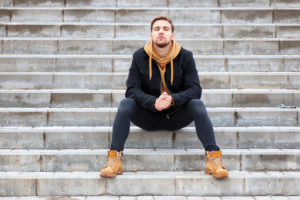 Person with short hair and beard sitting on stairs