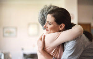 Close-up photo of older adult hugging adult with long hair