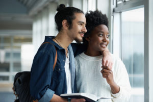 Couple looking out window smiling at something in the distance