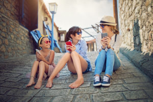 Mother and two daughters sit on roof with smar...