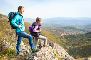 Mother and daughter stand proudly at the top of a cliff looking out in the dstance