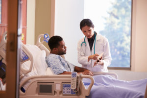 Doctor shows patient lying in hospital bed a tablet