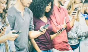 Young adults look at their smart phones while wearing different facial expressions.