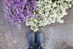 Top view of boots next to white and purple flowers