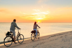 Couple enjoys twilight ride along beach on bikes