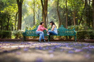 Mother and daughter sitting on bench at park, with some distance, talking