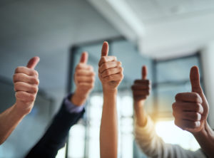 A group of people raise the thumbs-up sign in the air.