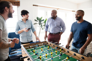 A group of men in button up shirts stand around a foosball table.