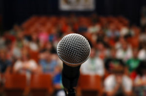 Close up of a microphone before a blurred-out crowd.