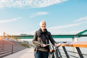 Person with short hair pushing bike along path looking up into the sky