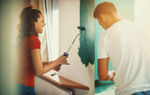 Couple working together talking and laughing while painting a room