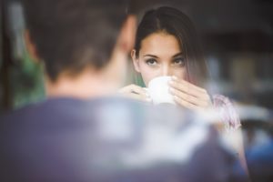 Woman sipping drink and looking at partner on date