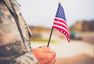 Close-up of American soldier holding a miniature American flag.