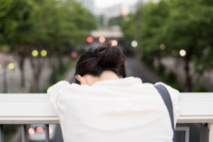 Women leans on bridge railing with her head down.