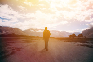 Rear view of traveler walking peacefully under a cloudy sunset