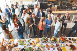 People mingle next to an elegant display of food.