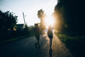 Couple holding hands and running into sunset on a country road