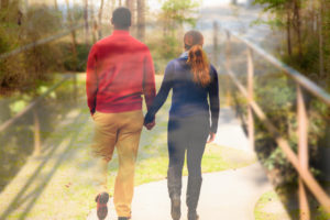 Rear view of people holding hands walking along bridge together