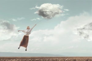 Person with long skirt flies through sky carried by cloud in dreamlike image