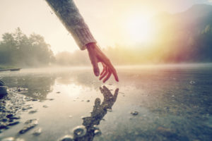 Finger touches surface of mountain lake