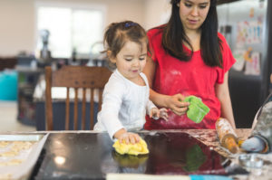 Parent stands back and watches child wipe down counter after baking