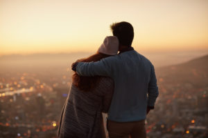 Rear view of couple standing on hillside looking out over city