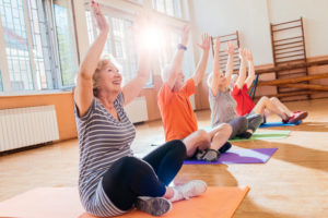 Group of seniors enjoying yoga class in sunlit room