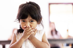 Girl covering her mouth with her hands, looking anxious