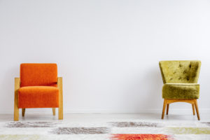 One orange and one green chair, sitting next to each other.