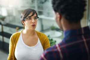 Woman looks at person she is talking to with a mildly annoyed expression on her face.