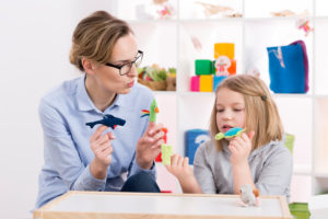 Counselor and child use animal figures to act out story in session of play therapy