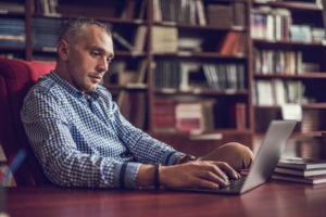 Adult with short hair does research on computer in library