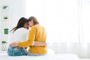 Couple sits on bed in embrace