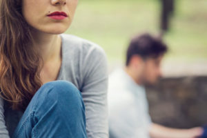 Cropped view of couple in the park looking in different directions, one out of focus