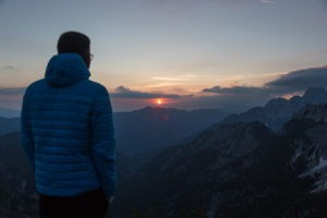 Hiker standing at top of mountain, watching a sunrise