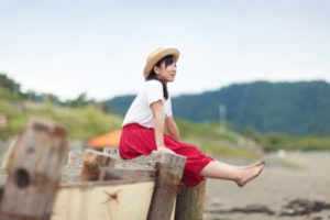 A young woman sits on some logs at the beach.