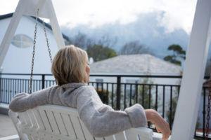 Woman sitting on porch swing, looking at view