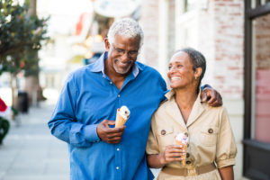 Older couple walks together eating ice cream, talking and laughing