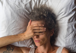 Close-up of woman covering her eyes to block out sunlight.