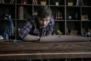 Man examines piece of leather on worktable, making sure it is exactly correct