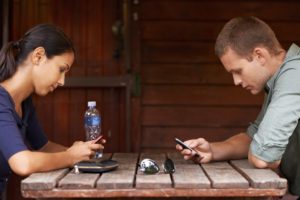 Two people on a date are distracted by their phones.