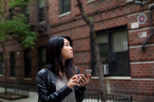 Girl in leather jacket explores city, using her phone for directions