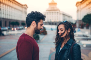 Downcast couple stands together, having serious conversation in the city