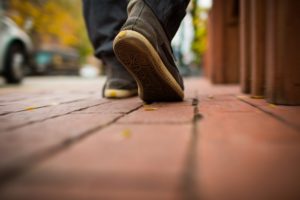 View of man's shoes as he walks on a sidewalk