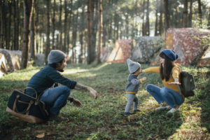 A baby practices walking from his father to his mother while on a camping trip.