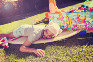 A grown man is passed out on the yard next to a kiddie pool.