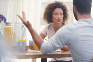 Couple sitting at their breakfast table, having an argument