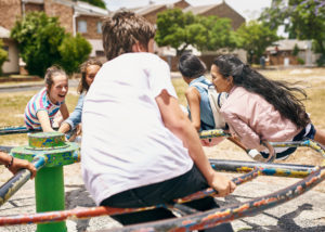 A boy in a white t-shirt plays with his classmates on the school playground.