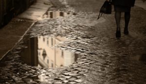 Lower view of professional woman walking on a rainy cobblestone road