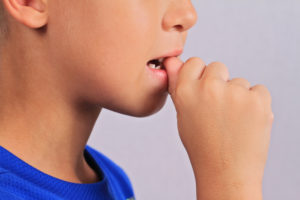 Close-up of a child biting their nail.